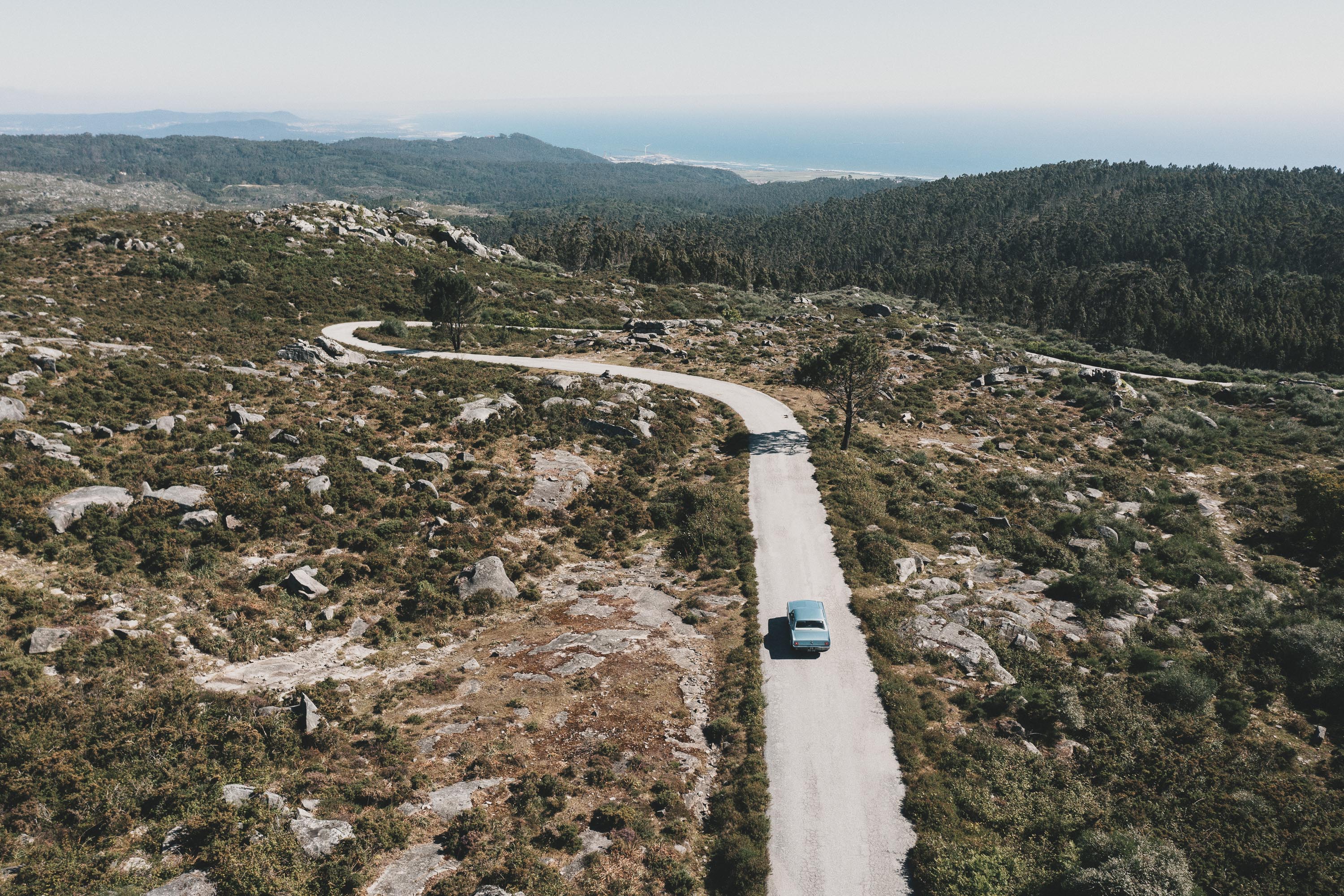 Old silver Mustang driving on a lonely  road in mediteran mountains